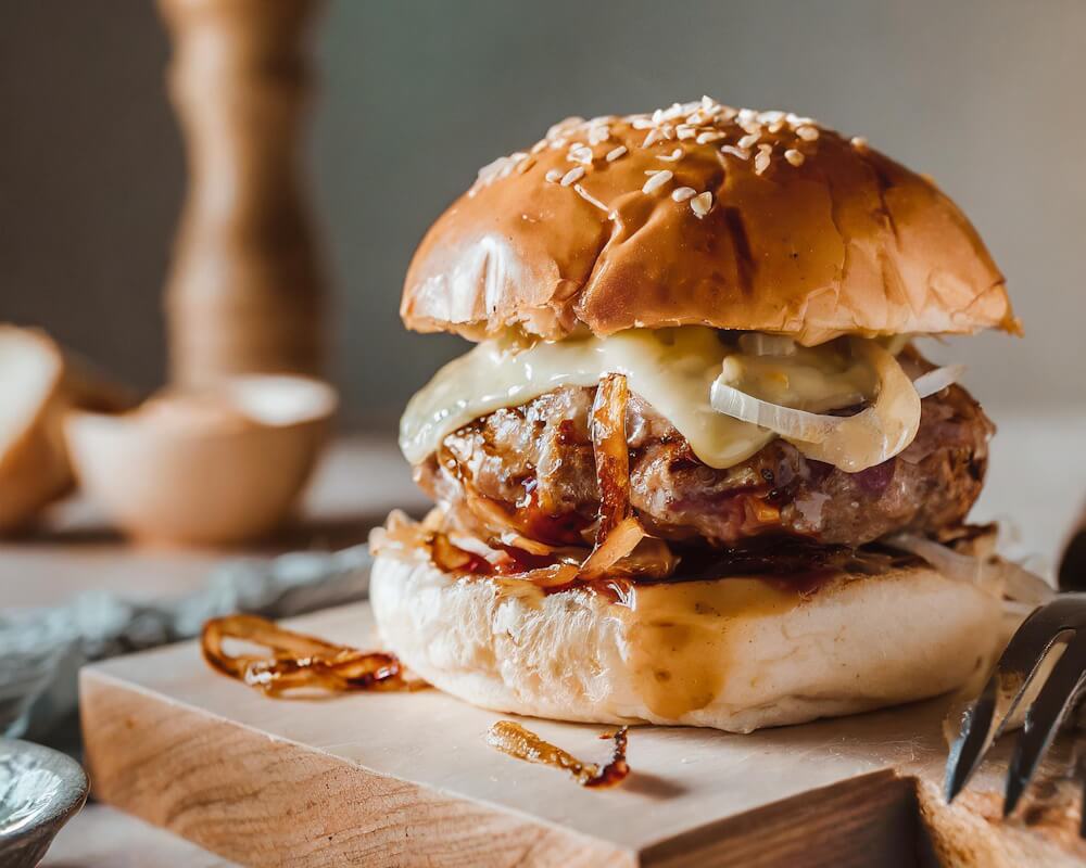 Cheeseburger lavet på en støbejernsplade og presset med en burgerpresser